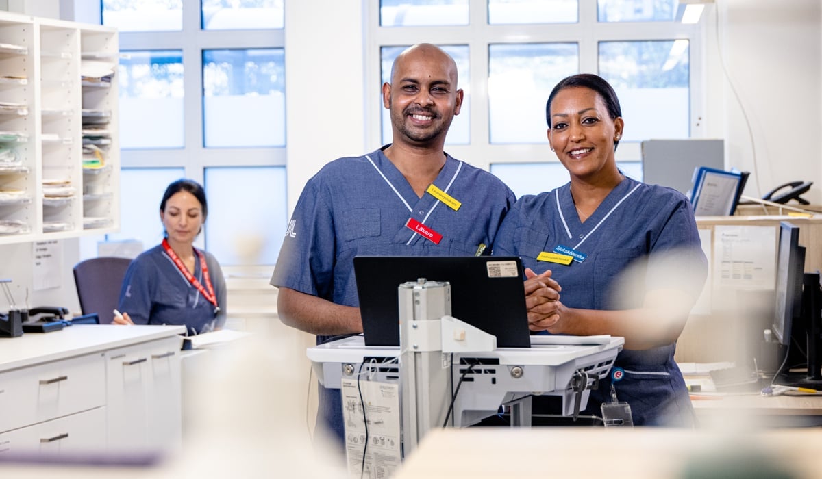 Två personer i blå tröjor tittar in i kameran