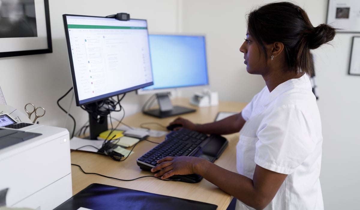 En kvinna står vid ett skrivbord och använder en dator.