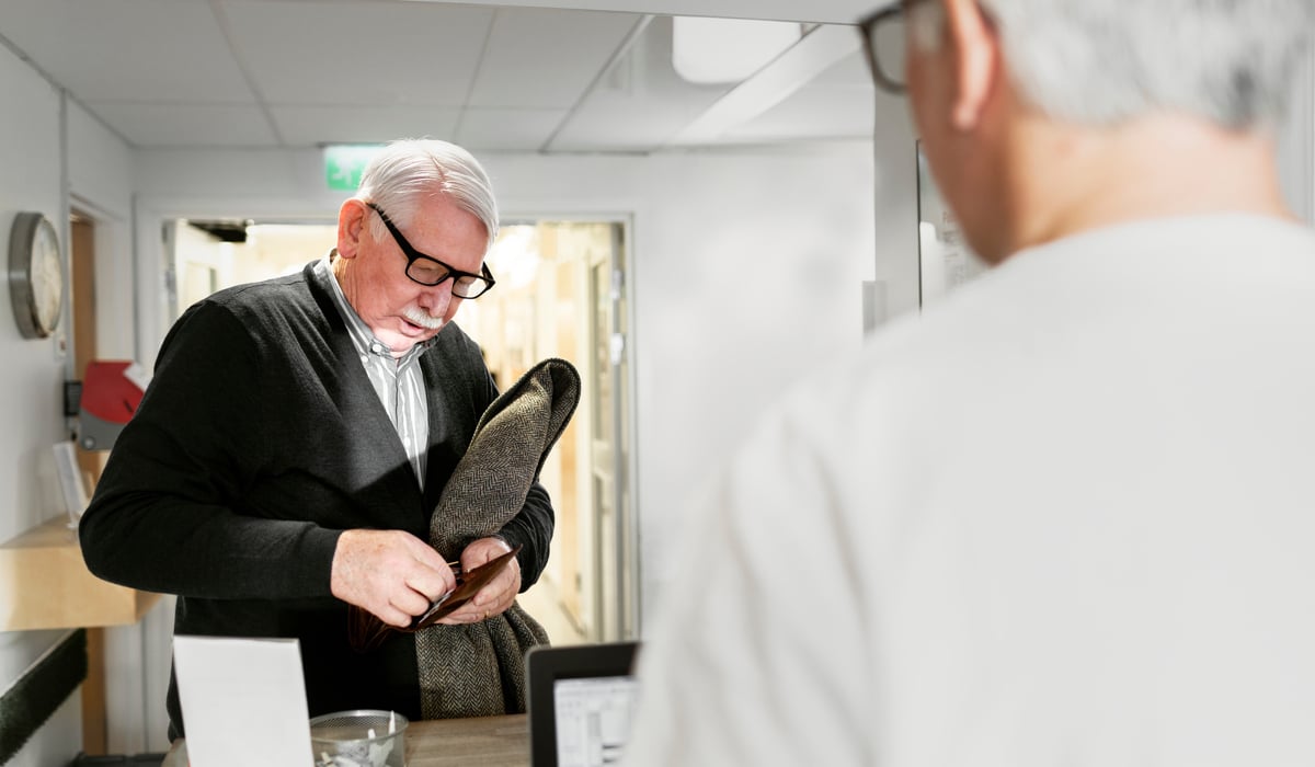 En man i vit skjorta tittar på ett par skor.