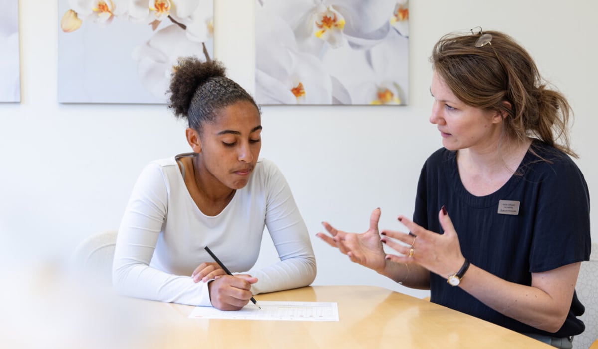 Två kvinnor sitter vid ett bord och pratar med varandra.