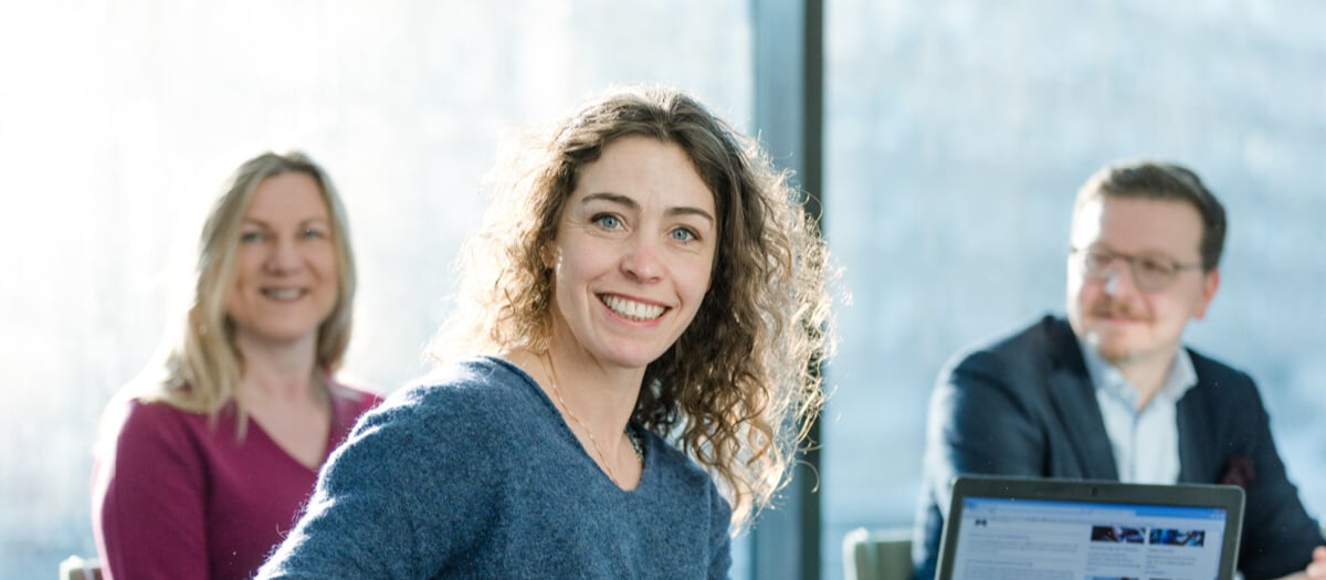 En grupp människor som sitter runt ett bord med en bärbar dator.