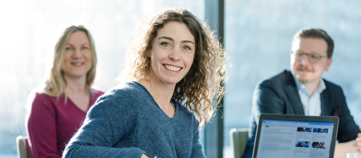 En grupp människor som sitter runt ett bord med en bärbar dator.