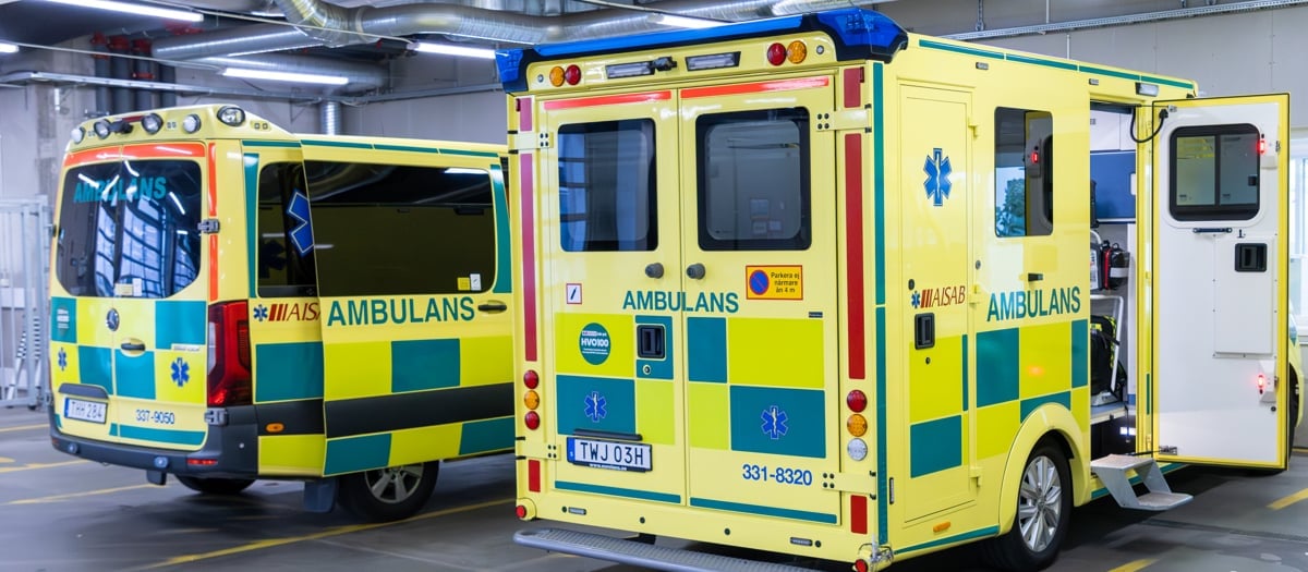 Två ambulanser står parkerade i ett parkeringsgarage.