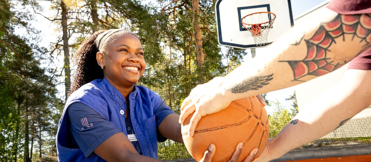 En kvinna som håller en basketboll framför en man.