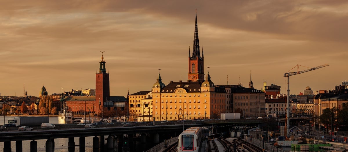 Ett tåg som färdas på järnvägsspår intill en stad.