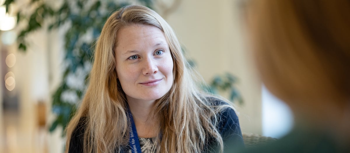 En kvinna som pratar med en annan person i ett rum.