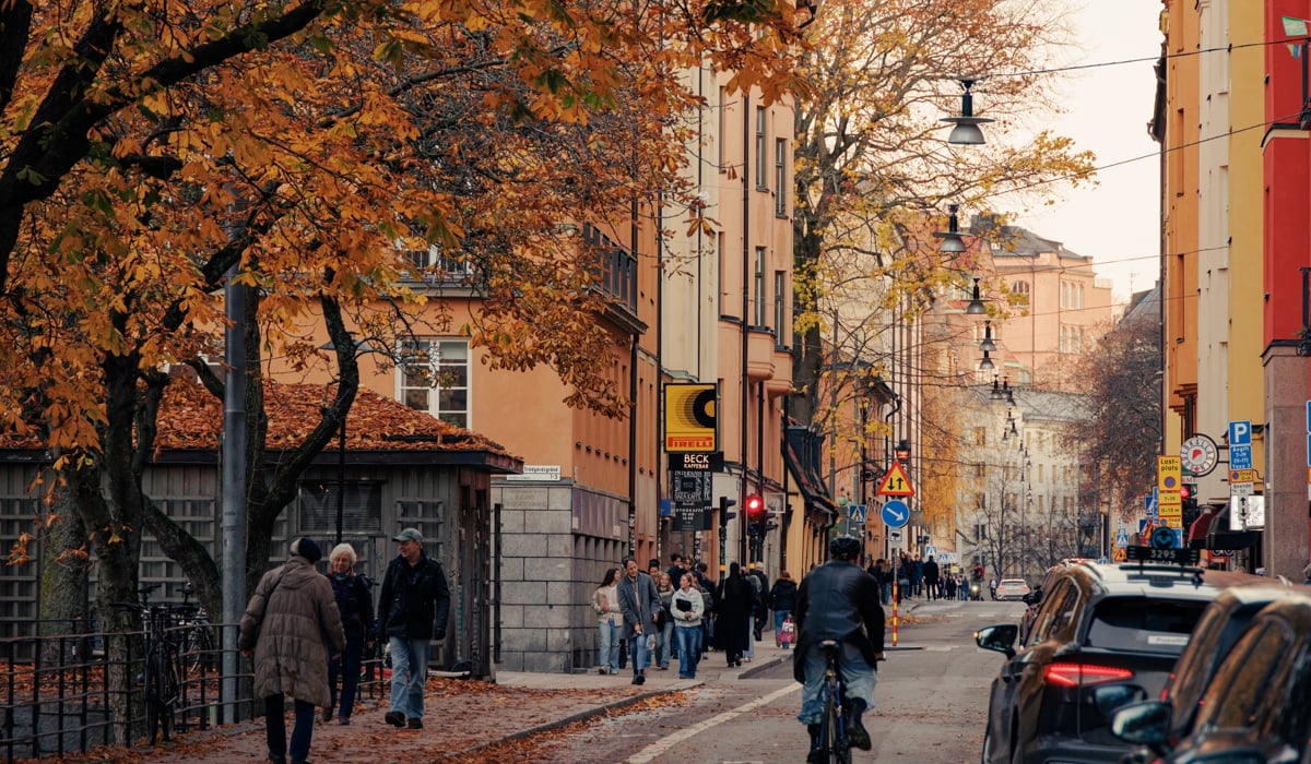 En man cyklar längs en gata bredvid höga byggnader.